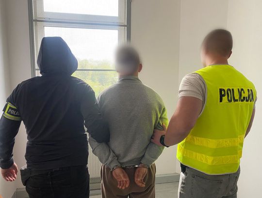 Garaż pełen narkotyków. 28-latek z Tomaszowa w areszcie po akcji kryminalnych Dwóch policjantów prowadzi zatrzymanego mężczyznę w kajdankach, twarze zamazane.