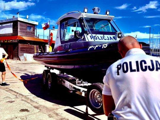 Policjant wodny na tle nowej łodzi patrolowej po pierwszym zwodowaniu.