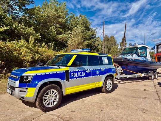 Land Rover Defender z przyczepą i łodzią policyjną – zestaw do działań w trudnym terenie.