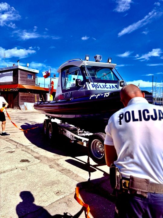 Policjant wodny na tle nowej łodzi patrolowej po pierwszym zwodowaniu.