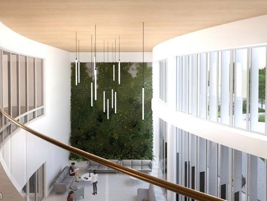 Sofa na pierwszym planie, nad nią balkon, po lewej zaokrąglone ściany i okna do zaplecza