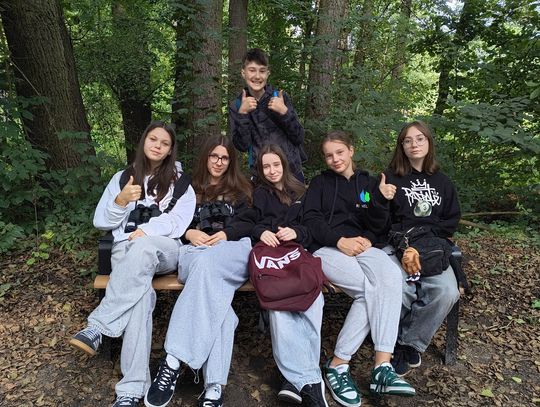 Leśny oddech – chwila wytchnienia Grupa uczniów SP6 odpoczywa na ławce w cieniu drzew – relaks i regeneracja podczas zajęć terenowych