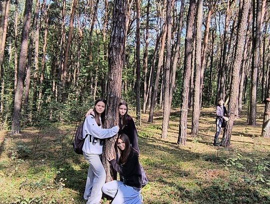 Moc drzew – uważność w praktyce Grupa uczennic przytula sosnę podczas kąpieli leśnych – zdrowy styl życia w Tomaszowie Mazowieckim