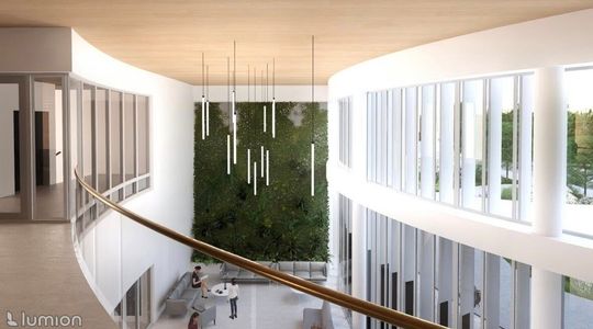 Sofa na pierwszym planie, nad nią balkon, po lewej zaokrąglone ściany i okna do zaplecza