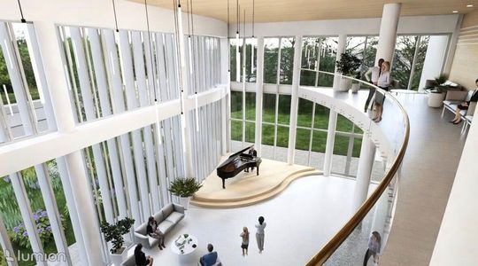 Widok z górnej galerii na zieloną ścianę i strefę siedzącą w holu, pionowe lampy zawieszone nad przestrzenią.