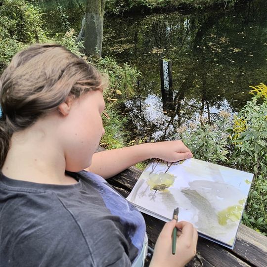 Uczennica szkicuje pejzaż nad wodą w rezerwacie Niebieskie Źródła – połączenie sztuki i biologii