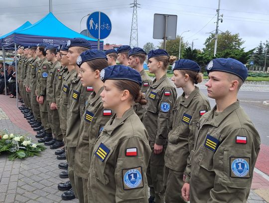Uczniowie klas mundurowych w oliwkowych mundurach i niebieskich beretach stoją w szeregu