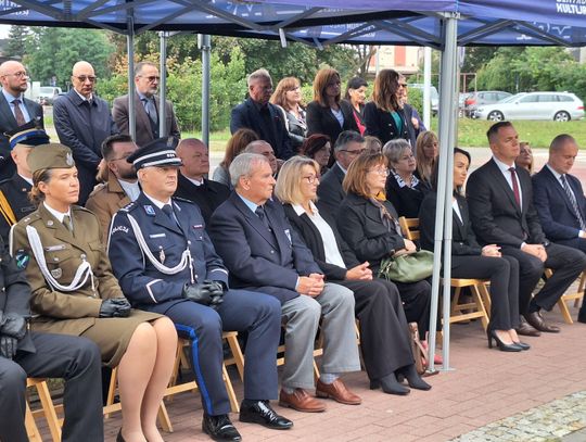 Rzędy krzeseł pod namiotem; w pierwszym rzędzie funkcjonariusze i zaproszeni goście w mundurach