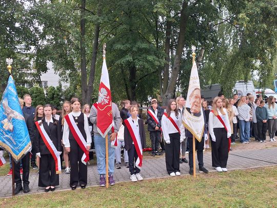 Uczniowie w szarfach trzymają sztandary szkolne podczas uroczystości