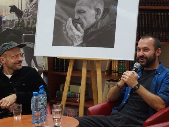 Dwóch autorów, w tle czarno-białe zdjęcie i regały biblioteki.