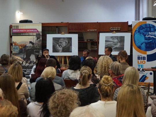 Widok sali od tyłu; panel z rozmówcami, banery MBP i „Niech fakty zatańczą”, fotografie na sztalugach.