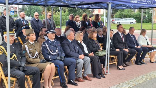 Rzędy krzeseł pod namiotem; w pierwszym rzędzie funkcjonariusze i zaproszeni goście w mundurach