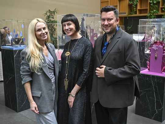 Trzy osoby pozują na tle gablot z biżuterią ORSKA x PARADYŻ.