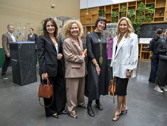 Cztery uczestniczki stoją przy ekspozycji breloków ORSKA x PARADYŻ.