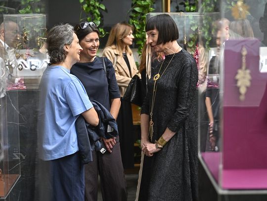 Uczestniczki rozmawiają wśród ekspozytorów z pozłacanymi brelokami.