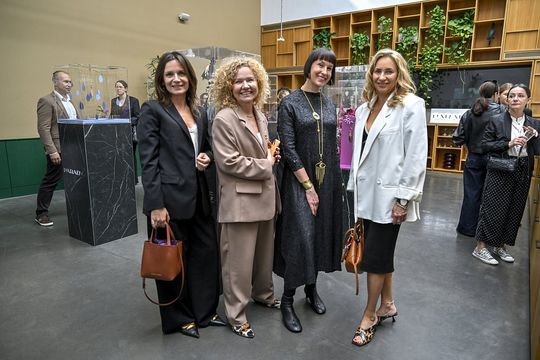 Cztery uczestniczki stoją przy ekspozycji breloków ORSKA x PARADYŻ.