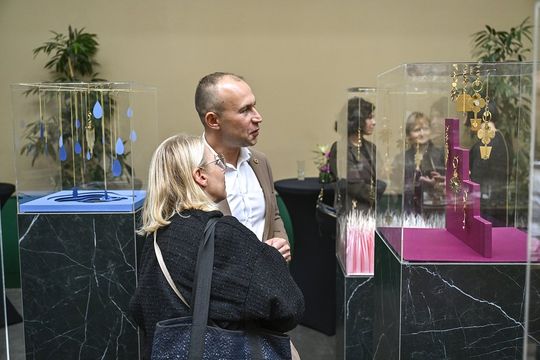 Dwoje gości ogląda gabloty z brelokami i biżuterią ORSKA x PARADYŻ w przestrzeni wystawowej.