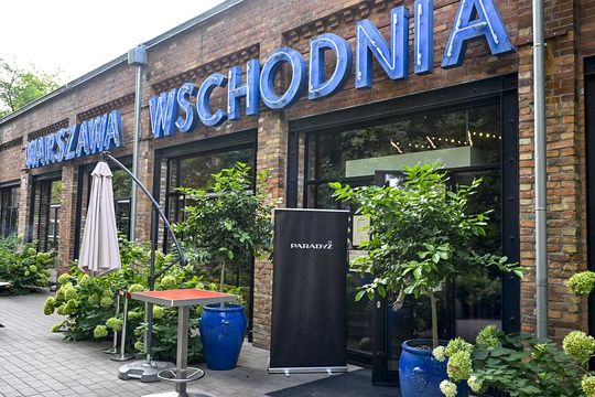 Wejście do restauracji Warszawa Wschodnia z szyldem i roll-upem Paradyż przed lokalem.