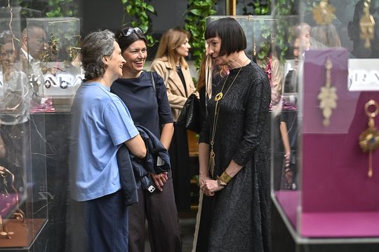 Uczestniczki rozmawiają wśród ekspozytorów z pozłacanymi brelokami.