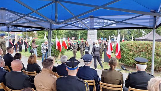 Perspektywa widowni – sztandary i flagi przy obelisku Uczestnicy pod namiotem obserwują uroczystość, widoczne flagi państwowe i obelisk