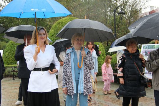 Pod parasolami – chwila wytchnienia przy planszach Dwie kobiety z parasolami podczas deszczowej uroczystości przy wystawie w spalskim parku.