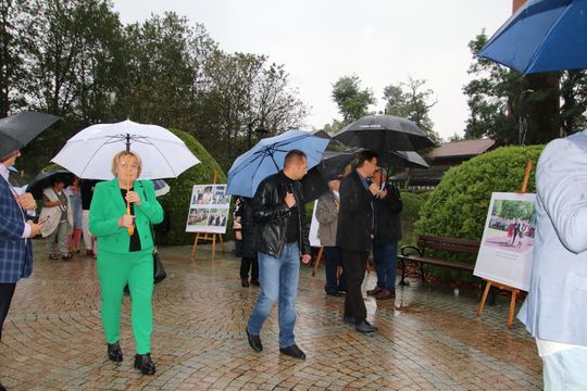 Wystawa w Spale Grupa osób przechadza się z parasolami obok plansz z historią Dożynek w Spale.