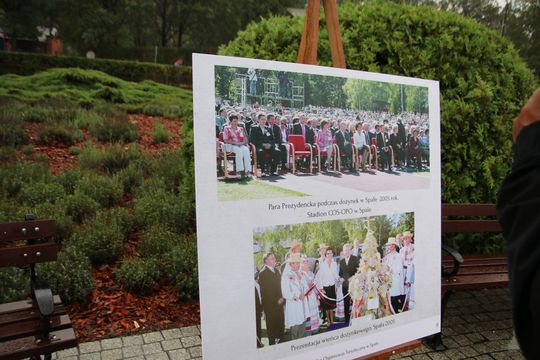 Dożynki 2005 na planszy — para prezydencka i wieniec Tablica z archiwalnymi zdjęciami Dożynek Prezydenckich 2005 ustawiona na sztaludze w parku.